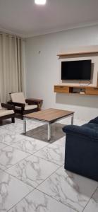 a living room with a table and a tv at Casa Selma Ubajara in Ubajara