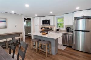 a kitchen with white cabinets and a kitchen island with bar stools at Dip and Dink Catskills Poolside Oasis in White Lake