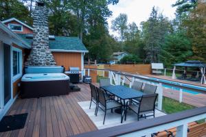 a deck with a hot tub and a table and chairs at Dip and Dink Catskills Poolside Oasis in White Lake