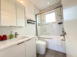 a white bathroom with a toilet and a sink at Vancouver Mandy Laneway Home in Vancouver