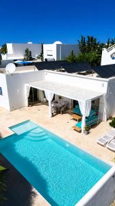 a swimming pool in front of a house with a white umbrella at Villa avec Piscine Privée à Djerba Dar Jafra in Houmt Souk