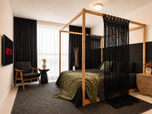 a bedroom with a canopy bed and a chair at Oasis on Monroe Aparthotel in Hollywood