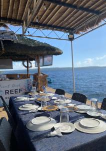 a table with plates and glasses on top of the ocean at Reef Resort - Samal Island View Unit B8 in Kaputian
