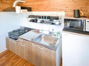 a small kitchen with a sink and a microwave at Sea Sky 赤崎 in Yoron