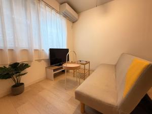 a living room with a couch and a tv and a table at ura BETTEi 別邸 in Okayama
