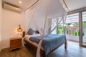 a bedroom with a canopy bed and a window at Villas Shiva, Cahaya & Bulan Complex - Bingin, Uluwatu in Uluwatu +80 photos