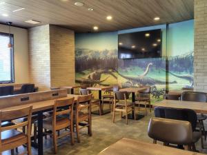 a restaurant with tables and chairs and a large mural at Hotel cooju Fukui in Sakai