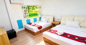 a room with two beds and a window at BG prosper Hostel in Ban Don Muang (1)