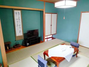 a living room with a table and a tv at ウテナ2 in Ito