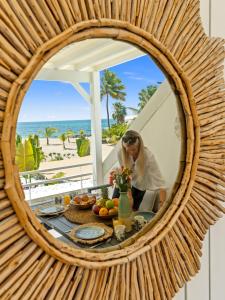 a woman sitting at a table in front of a mirror at Shell Beach - Magnifique Loft sur la plage in Baie Nettle