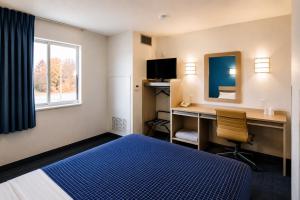a hotel room with a bed and a desk and a window at Econo Lodge Menomonie in Menomonie