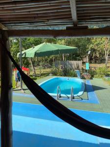 a hammock in front of a pool with an umbrella at Sitio Piruetas in Santana do Livramento