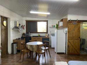 a kitchen with a table and a white refrigerator at Sitio Piruetas in Santana do Livramento