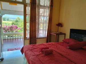 a bedroom with a red bed and a large window at Hobbit Hill in Ruteng