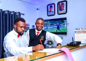 two men sitting at a desk signing a paper at Executive Private Bed and Bath in Otta