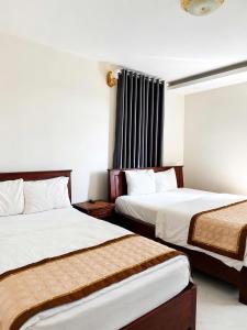 a hotel room with two beds and a window at Hoàng Khiêm Hotel in Mỹ Thạch