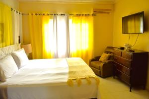 a bedroom with a bed and a chair and a television at Embassy Royale in Kingston +20 photos