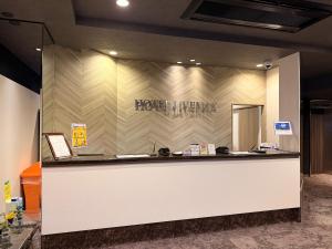 a hotel lobby with a hotel sign on a wall at HOTEL LiVEMAX BUDGET Hiratsuka Ekimae in Hiratsuka