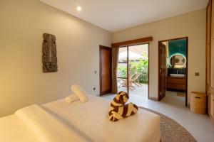 a stuffed animal sitting on a bed in a bedroom at Coco Luxury Villas in Ubud