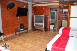 Ein Zimmer aus roten Ziegelsteinen mit einem Bett und einem Fernseher in der Unterkunft Rivera Maya Hotel Campestre in Rivera