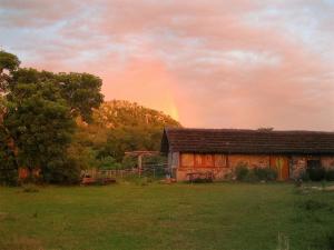 un antiguo granero con un arco iris en el fondo en Tao Sierras De Aigua en Aiguá