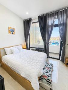 a bedroom with a large bed and a large window at Đầm Nại Hotel in Ninh Hải