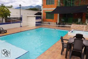 ein Schwimmbad mit Tisch und Stühlen neben einem Gebäude in der Unterkunft Rivera Maya Hotel Campestre in Rivera