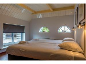 a bedroom with a large bed with two windows at Lovely Holiday Home in Texel near Sea in Oost