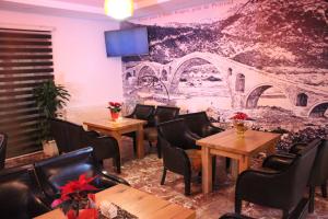 a restaurant with tables and chairs and a wall with a mural at Oda Kuksit Hotel in Kukës