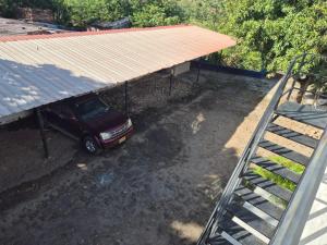 a car parked under a building with a metal roof at Brisas Alojamiento in Gualanday