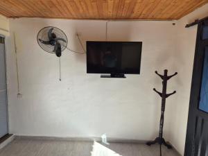 a flat screen tv on a wall with a fan at Brisas Alojamiento in Gualanday