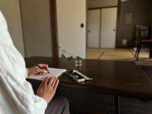 a person sitting at a table writing in a notebook at sikari Vacation STAY 95401v in Takashima