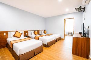a hotel room with three beds and a flat screen tv at Eagle Sầm Sơn Hotel in Sầm Sơn