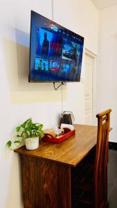 a television on a wall above a wooden table at The Continental Hotel in Seeduwa