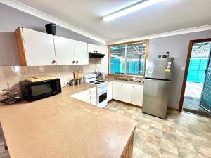 a kitchen with a stainless steel refrigerator and white cabinets at Sunshine on Heath -Pet Friendly in Evans Head
