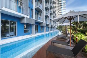 a swimming pool with chairs and an umbrella next to a building at BLU Diamond Cha Am in Ban Bo Khaem