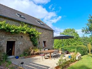 a table with an umbrella next to a building at Le refuge des oiseaux in Langonnet