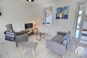 a living room with a couch and chairs and a tv at Le clos rucharet in Saint-Carreuc