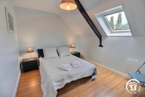 a bedroom with a bed with white sheets and a window at Le clos rucharet in Saint-Carreuc