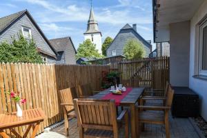 a wooden table and chairs on a patio with a church at Ferienwohnungen Haus Cramer in Winterberg