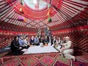 a group of people sitting in a red tent at Guest house and Yurt camp "Ailuu" in Tong