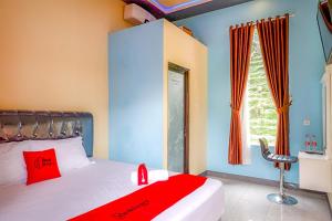 a bedroom with a bed with red pillows and a window at RedDoorz @ Gerbang Dieng Plateau Area in Wonosobo