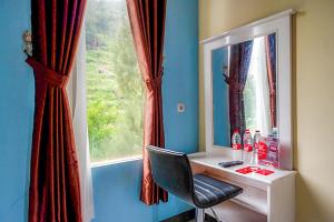 a desk with a chair in front of a window at RedDoorz @ Gerbang Dieng Plateau Area in Wonosobo