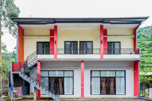 a house with red columns and a balcony at RedDoorz @ Gerbang Dieng Plateau Area in Wonosobo +11 photos