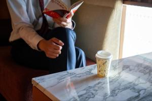 a person reading a book and a cup of coffee at Iwaki Washington Hotel in Iwaki