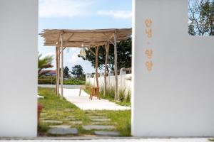 a wooden pergola with a bench on a sidewalk at Yangyang Staydaro in Yangyang