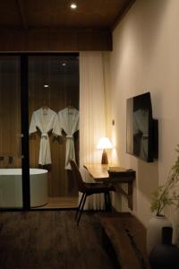 a room with a bath tub and a table and a desk at Inlaya Ratchaburi in Ratchaburi
