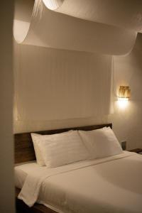 a bedroom with a white bed with white sheets at Inlaya Ratchaburi in Ratchaburi