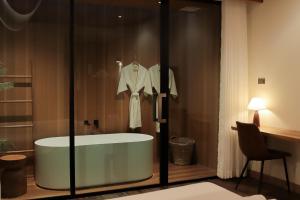 a bathroom with a bath tub and a dress on a rack at Inlaya Ratchaburi in Ratchaburi