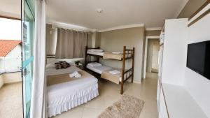 a small room with two beds and a tv at Pousada Recanto do Cowboy in Penha +30 photos